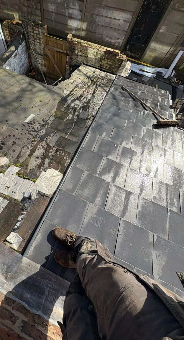 Grey roof tiles at the chimney junction during slate roof installation on a terraced home