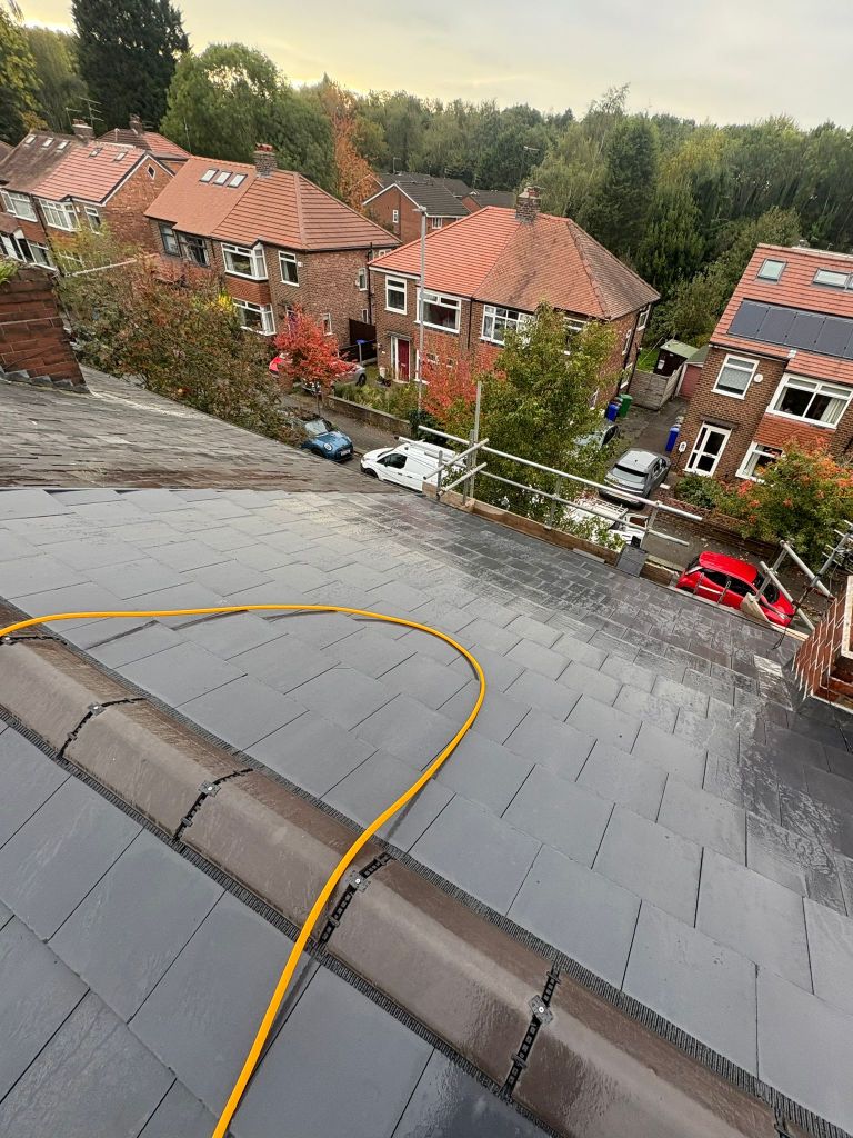 Grey roof tiles viewed from the roof edge above neighbouring brick homes