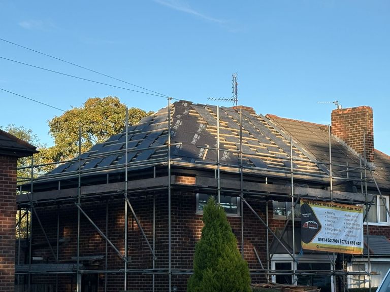 Roof stripped back to timber framing with scaffolding around a brick home