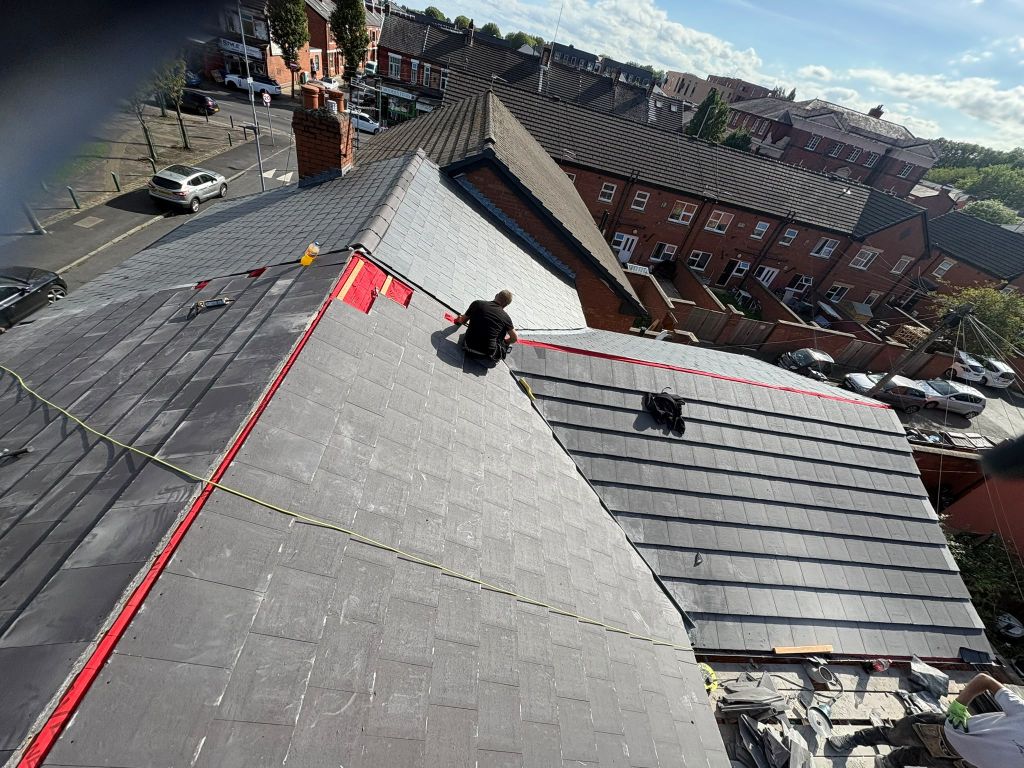Grey roof covering being installed on a terraced home, with ridge and junction work still in progress